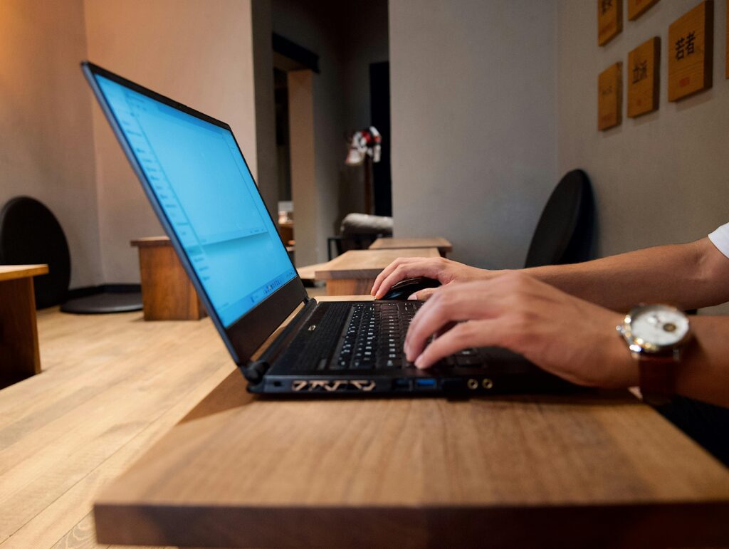 Gravit Designer software used for vector illustration" Hands typing on a laptop in a modern coffee shop, emphasizing remote work flexibility.