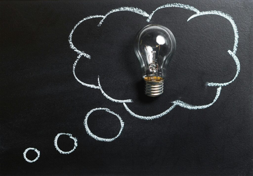 alt="idea symbol representing reforming education and creativity" Light bulb laying on chalkboard with drawn thought bubble, symbolizing creative ideas.