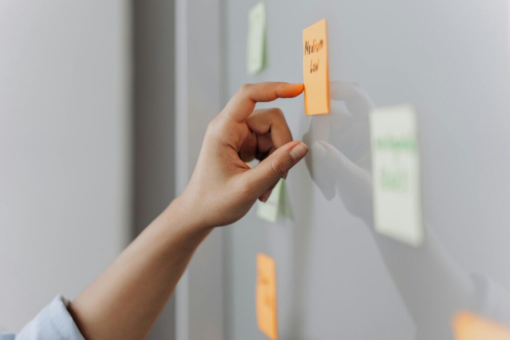 pexels photo 6592367 6592367 A hand placing a sticky note on a reflective surface in an office setting.